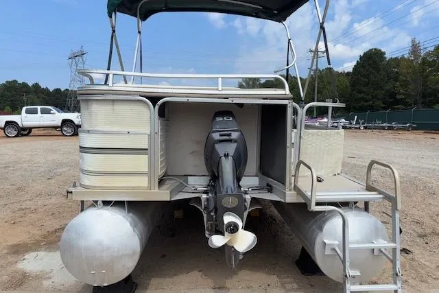 Slide: The Image of 1997 Grumman 24 FS pontoon boat with outboard motor, parked on gravel lot. - 6