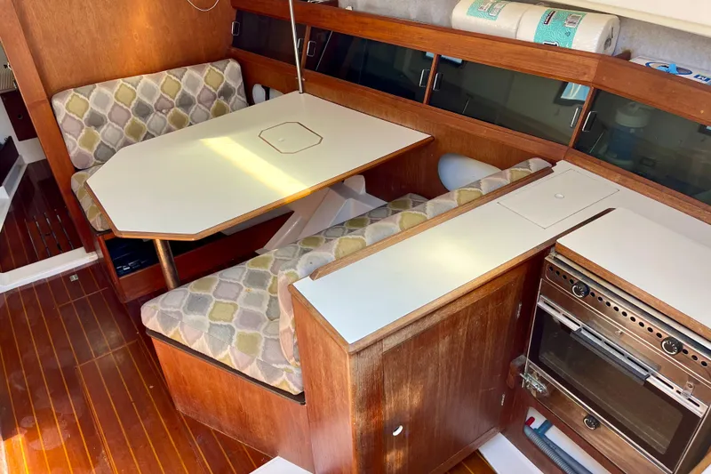 Slide: The Image of 1985 Hunter 31 yacht interior with dining area, cushioned seating, and compact kitchen. - 13