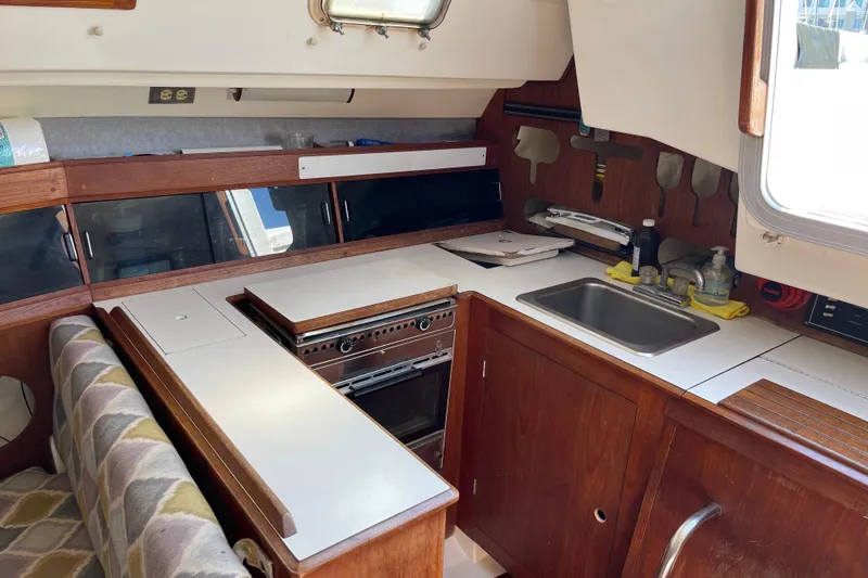 Slide: The Image of Interior of 1985 Hunter 31 sailboat galley with stove, sink, and wooden cabinetry. - 17