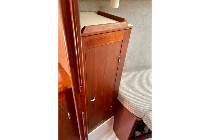 Slide: The Image of 1985 Hunter 31 interior with wooden cabinet and striped cushion seating. - 29