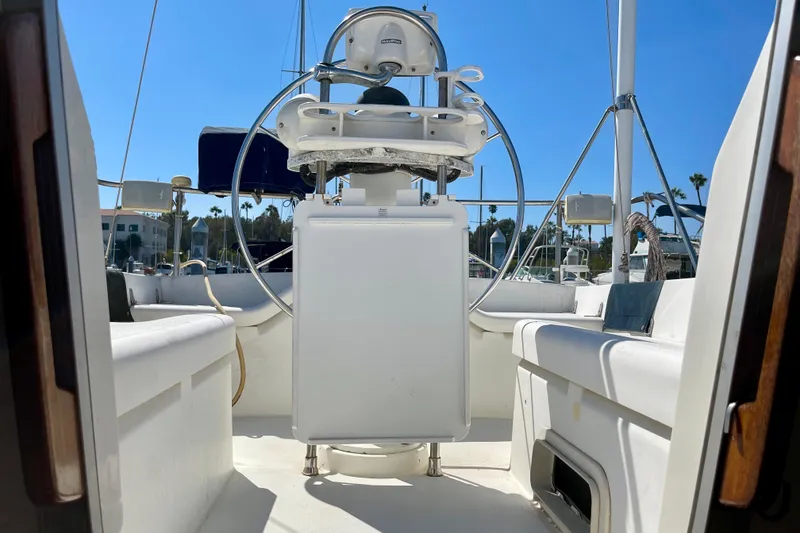 Slide: The Image of 1985 Hunter 31 sailboat cockpit with steering wheel, docked under clear blue sky. - 30