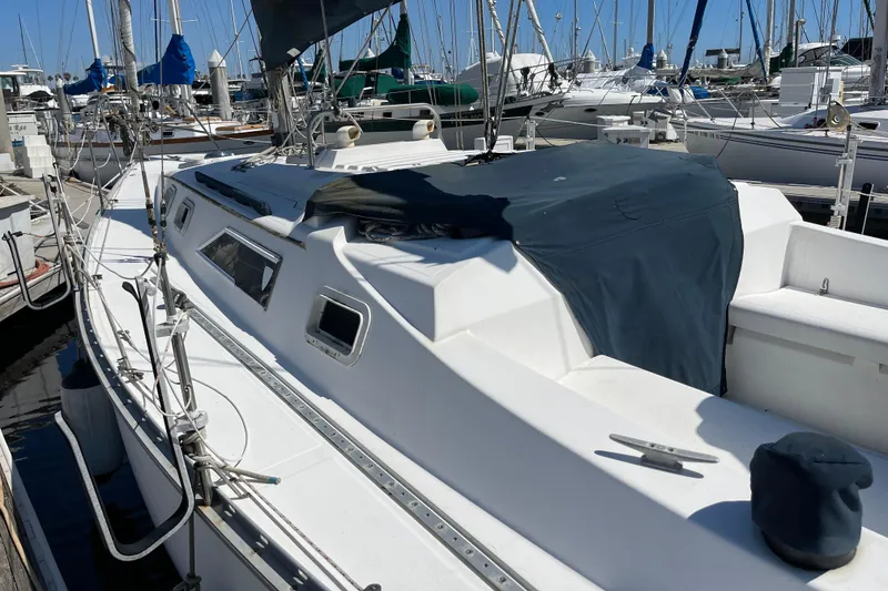 Slide: The Image of 1985 Hunter 31 sailboat docked in marina, featuring white deck and blue cover. - 5