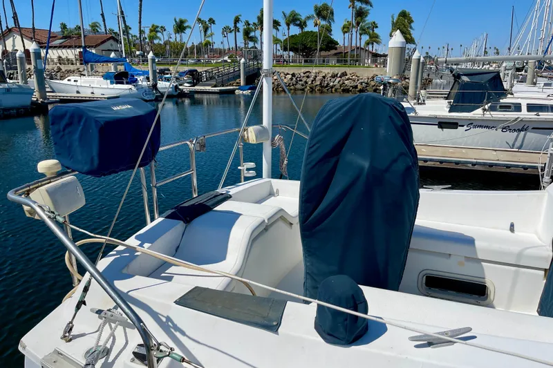 Slide: The Image of 1985 Hunter 31 sailboat docked in marina, featuring covered cockpit and clear blue sky. - 6