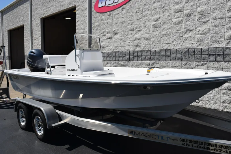 Slide: The Image of 2026 Frontier 180 boat on trailer outside a building, featuring a sleek design. - 2
