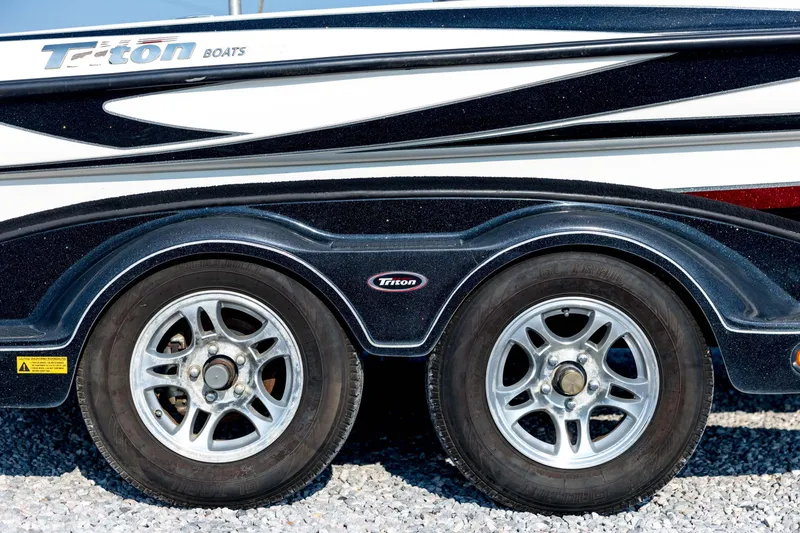 Slide: The Image of 2011 Triton 20XS DC boat trailer with dual wheels on gravel surface. - 13