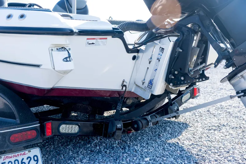 Slide: The Image of 2011 Triton 20XS DC boat trailer hitch and motor detail on gravel surface. - 20