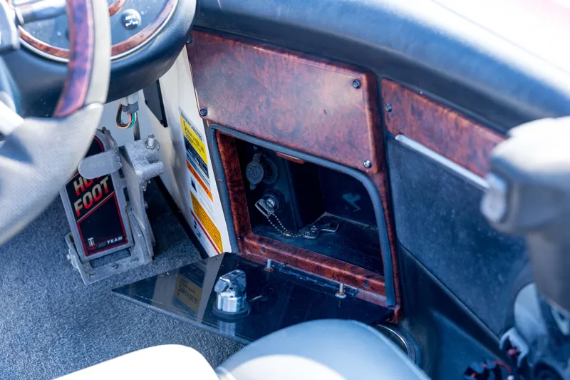 Slide: The Image of 2011 Triton 20XS DC boat dashboard with open storage compartment and foot pedal. - 63