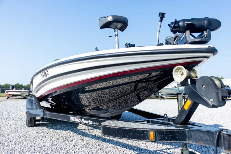 Slide: The Image of 2011 Triton 20XS DC boat on trailer, parked on gravel lot under clear blue sky. - 9