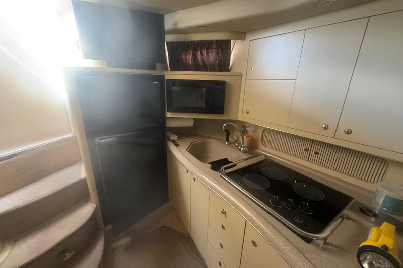 Slide: The Image of 1999 Sea Ray Sundancer 400 yacht kitchen with stove, sink, and cabinets. - 22