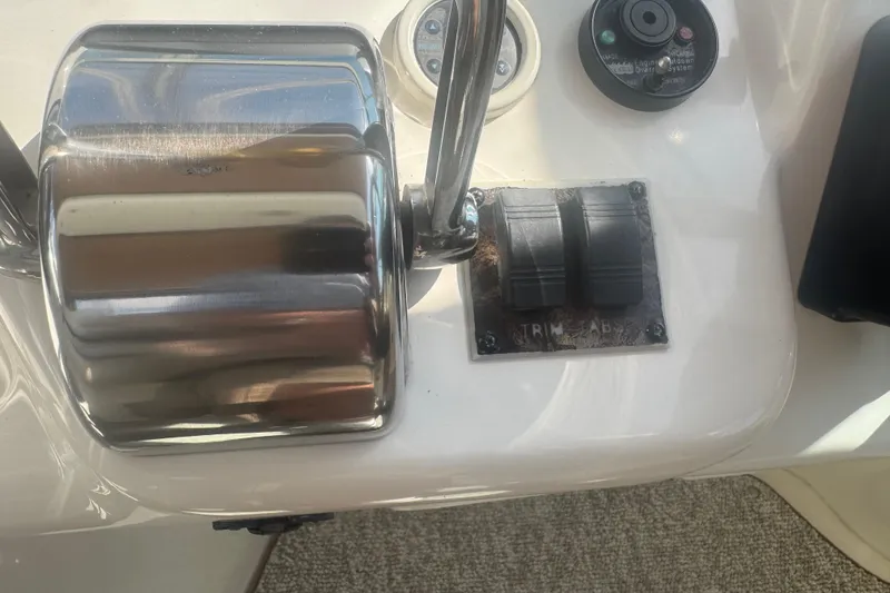 Slide: The Image of 1999 Sea Ray Sundancer 400 throttle controls and trim tabs on boat dashboard. - 31