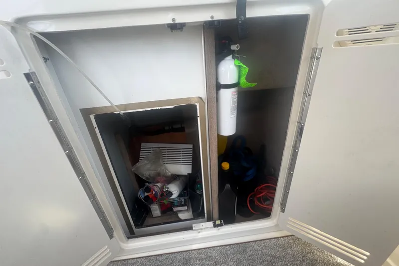 Slide: The Image of 1999 Sea Ray Sundancer 400 storage compartment with fire extinguisher and supplies. - 32