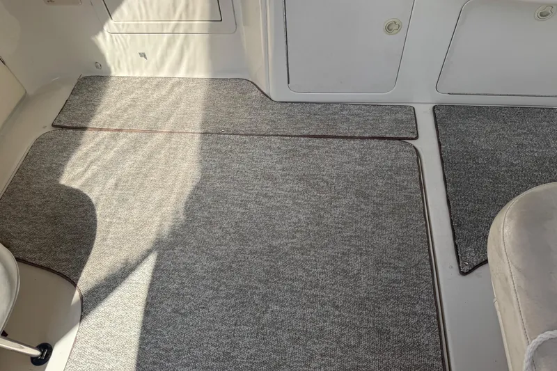 Slide: The Image of 1999 Sea Ray Sundancer 400 interior with gray carpeted flooring and white seating. - 33