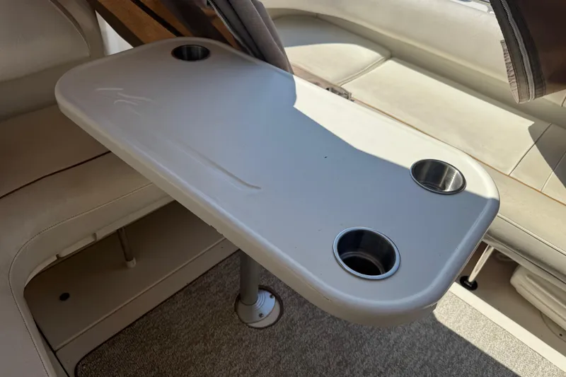 Slide: The Image of 1999 Sea Ray Sundancer 400 interior table with cup holders, beige seating, and carpeted floor. - 37
