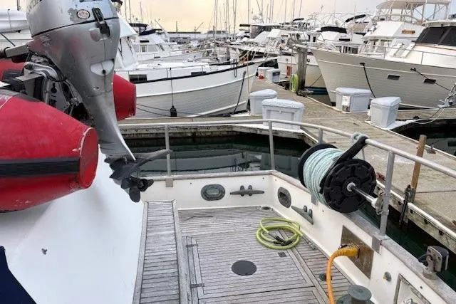 Slide: The Image of 1984 Grand Banks Classic yacht docked at marina with outboard motor and deck equipment. - 13