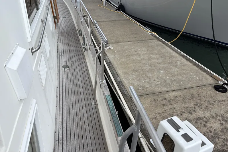 Slide: The Image of 1984 Grand Banks Classic yacht docked, showing side deck and marina walkway. - 14