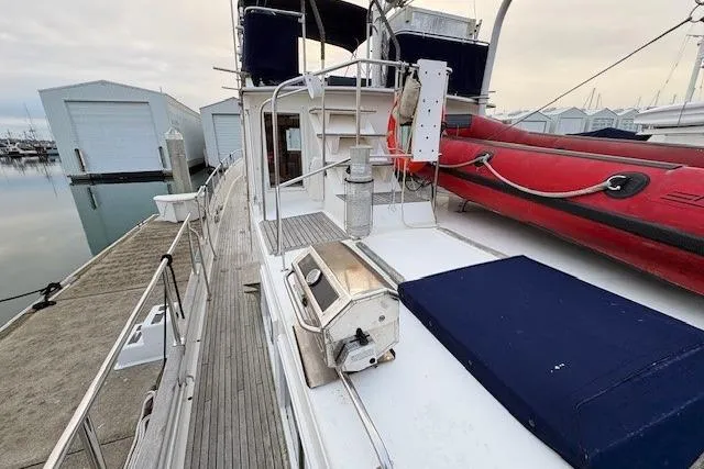 Slide: The Image of 1984 Grand Banks Classic yacht docked, featuring deck view with red dinghy and blue cushions. - 16