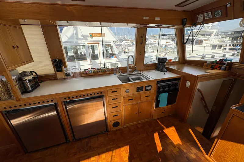 Slide: The Image of 1984 Grand Banks Classic yacht kitchen with wooden cabinetry, stainless appliances, and marina view. - 24