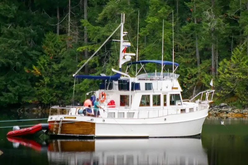 Slide: The Image of 1984 Grand Banks 49 Classic yacht anchored in a serene forested lake. - 3