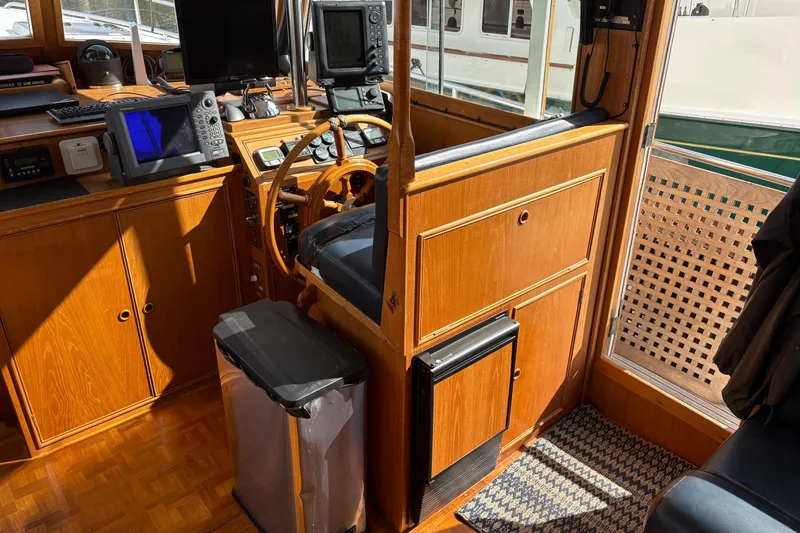 Slide: The Image of 1984 Grand Banks Classic yacht interior with wooden helm, navigation equipment, and sunlight streaming in. - 31