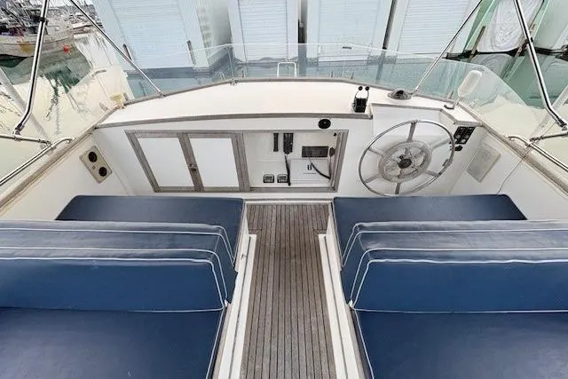 Slide: The Image of 1984 Grand Banks Classic boat helm with blue seating and wooden deck. - 4