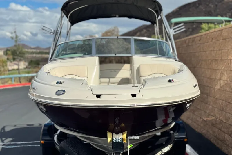 Slide: The Image of 2008 Sea Ray 200 Sundeck boat on trailer, parked outdoors with scenic background. - 2