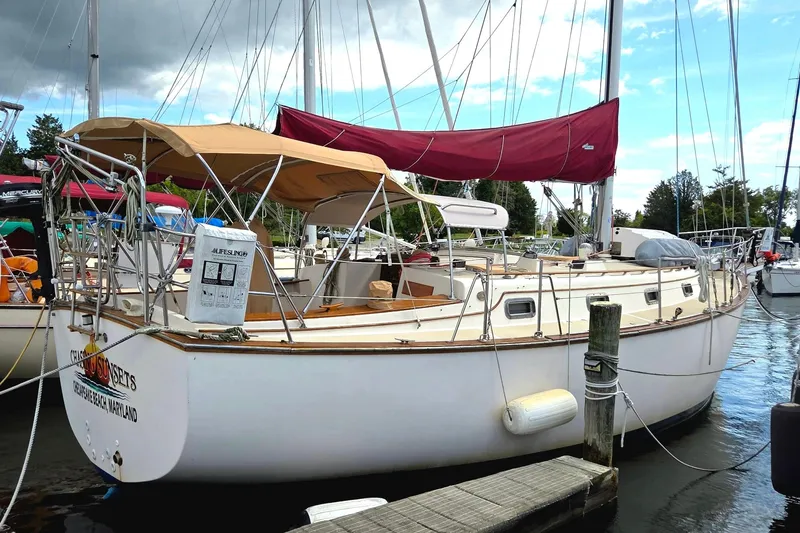 The Image of 1989 Island Packet 38 sailboat docked with tan canopy and red sail. - 0
