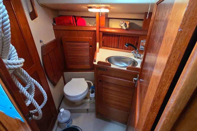 Slide: The Image of 1989 Island Packet 38 sailboat bathroom with wooden cabinetry and compact design. - 13