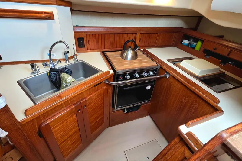 Slide: The Image of 1989 Island Packet 38 yacht kitchen with wooden cabinetry, stove, and sink. - 7