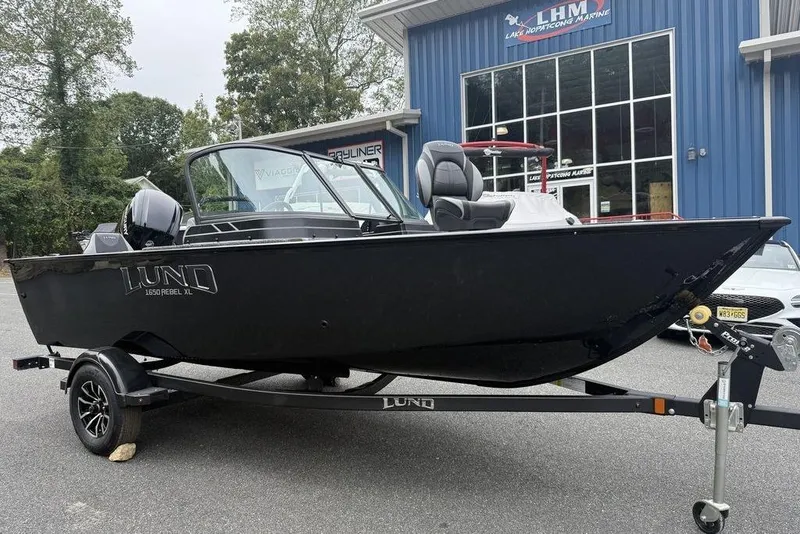 Slide: The Image of 2026 Lund 1650 Rebel SS boat on trailer outside marine shop. - 2