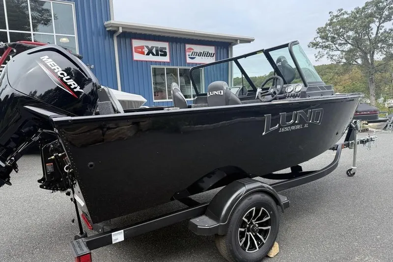 Slide: The Image of 2026 Lund 1650 Rebel SS boat with Mercury engine on trailer, parked outside dealership. - 4
