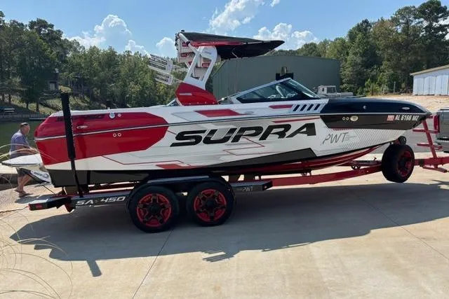 Slide: The Image of 2017 Supra SA450 boat in red and white, parked under a metal roof. - 2