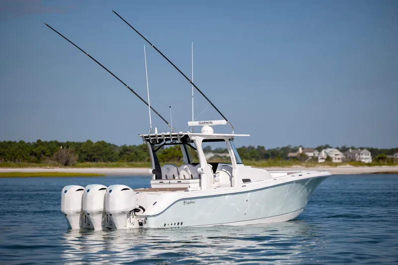 Slide: The Image of 2021 Edgewater 370CC boat with triple engines on calm water, near shoreline. - 10