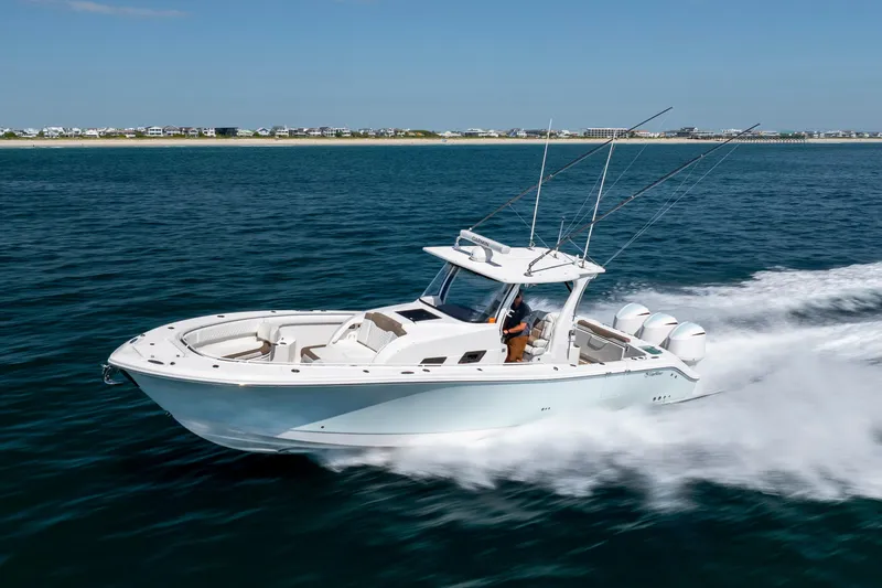 Slide: The Image of 2021 Edgewater 370CC boat cruising on open water with coastal background. - 20