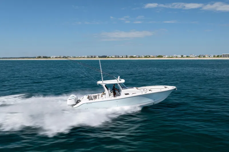 Slide: The Image of 2021 Edgewater 370CC boat cruising on open water near a distant shoreline. - 25