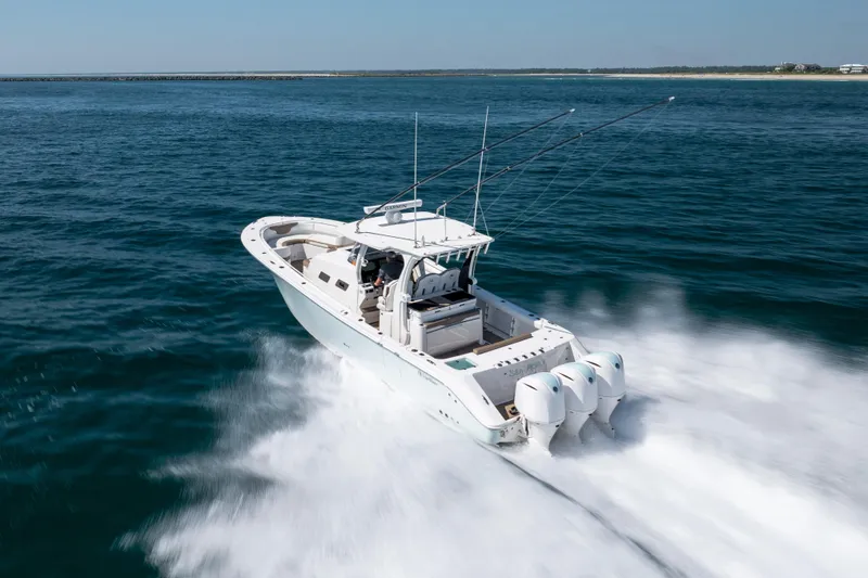 Slide: The Image of 2021 Edgewater 370CC boat speeding on open water with triple outboard engines. - 28