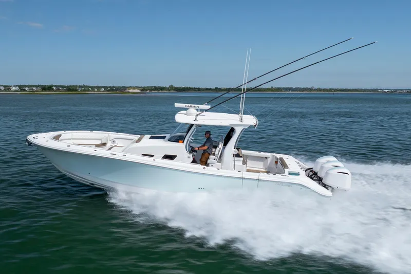 Slide: The Image of 2021 Edgewater 370CC boat cruising on open water, featuring dual outboard engines. - 31