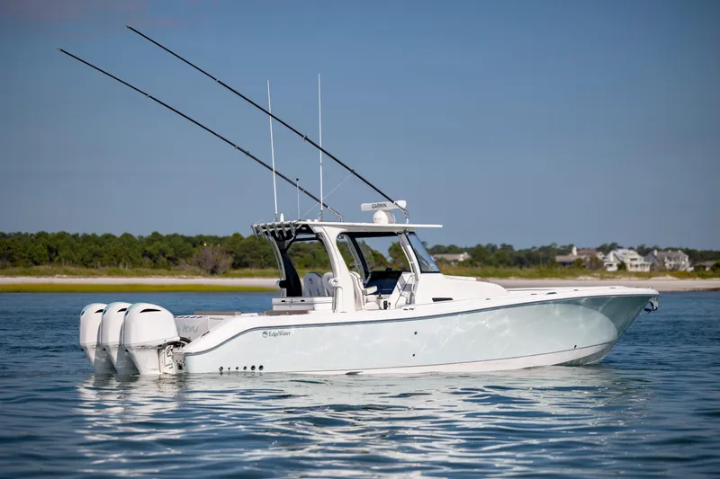 Slide: The Image of 2021 Edgewater 370CC boat on calm water with triple outboard engines. - 4