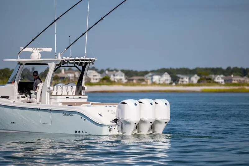 Slide: The Image of 2021 Edgewater 370CC boat with triple engines cruising near coastal homes. - 5
