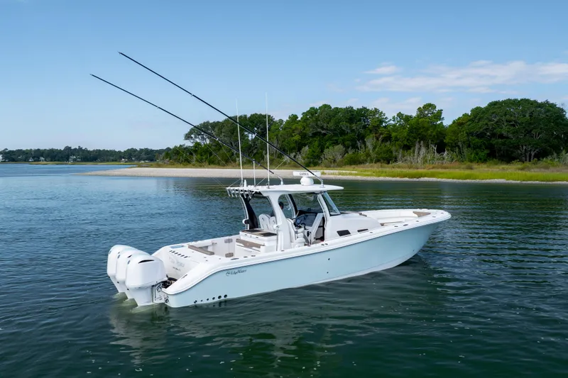 Slide: The Image of 2021 Edgewater 370CC boat on calm water near a lush shoreline. - 6