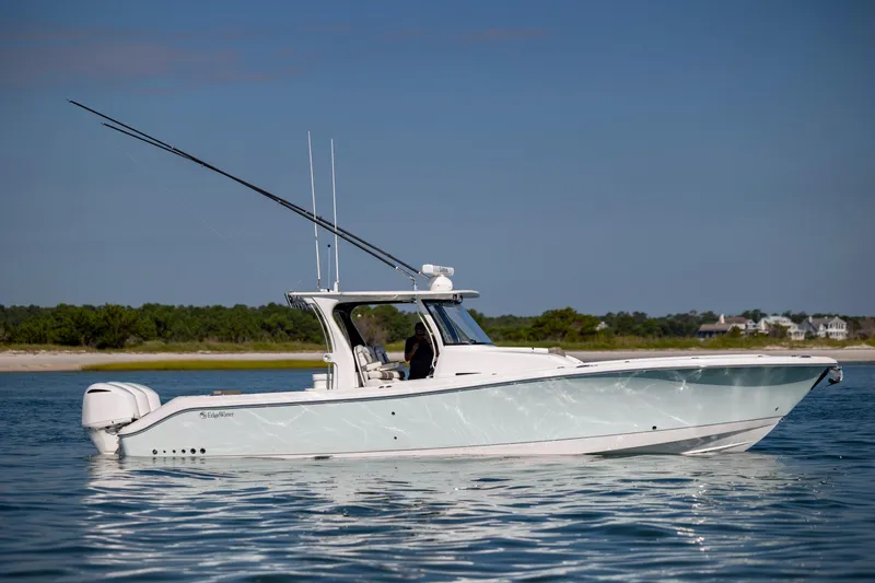 Slide: The Image of 2021 Edgewater 370CC boat on calm water with scenic shoreline background. - 9