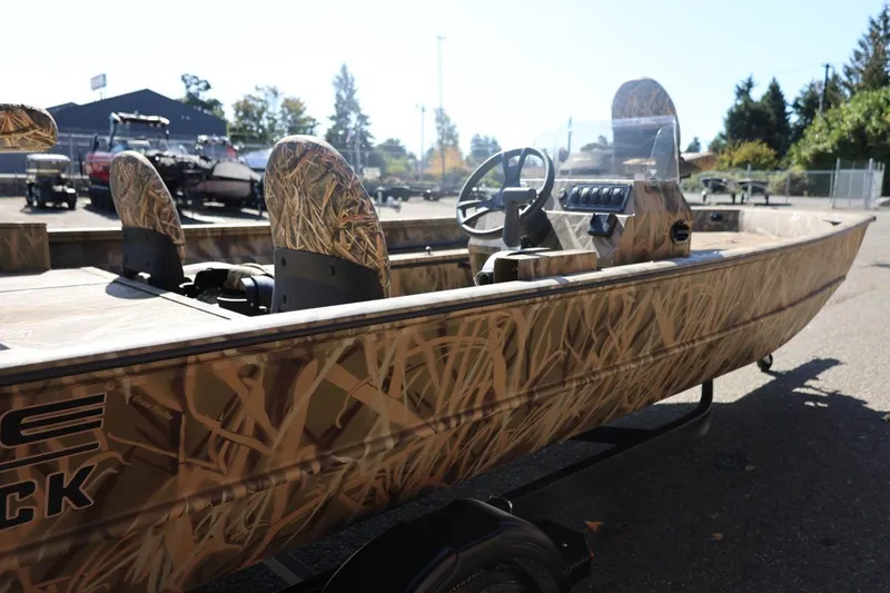 Slide: The Image of 2026 Lowe Roughneck RX2070 SC boat with camouflage design, parked outdoors on a sunny day. - 24
