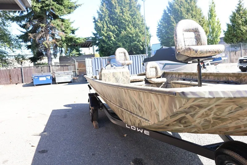 Slide: The Image of 2026 Lowe Roughneck RX2070 SC boat with camouflage design in a parking area. - 25