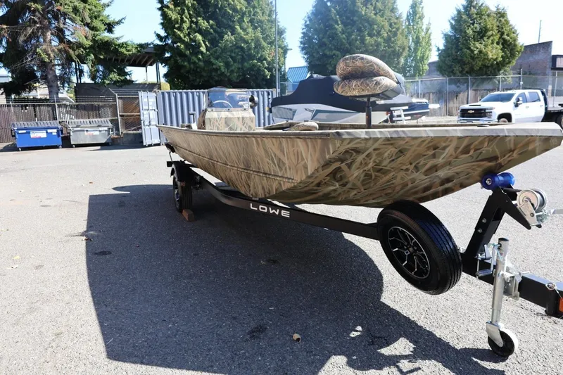 Slide: The Image of 2026 Lowe Roughneck RX2070 SC boat with camouflage design on a trailer in a parking lot. - 4