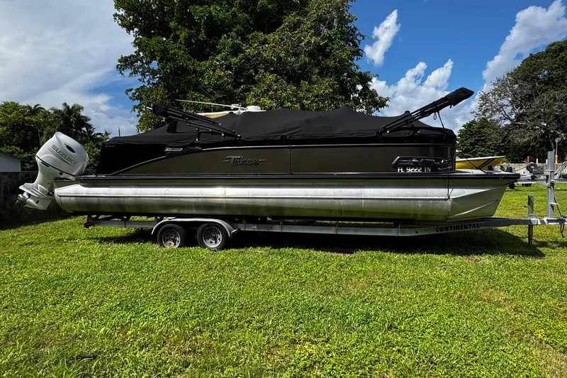 The Image of 2023 Tahoe Pontoon Cascade Platinum Quad Lounger on trailer, parked on grass. - 1