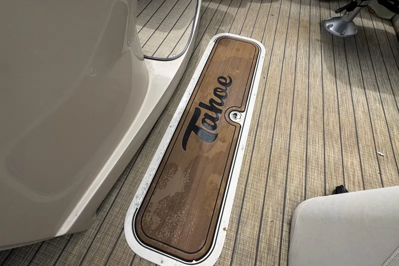 Slide: The Image of 2023 Tahoe Pontoon Cascade Platinum Quad Lounger deck with logo on wooden panel. - 17