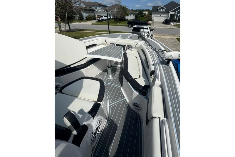Slide: The Image of 2022 Tidewater 272 CC Adventure boat interior with seating and table, parked in a residential area. - 12