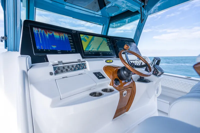 Slide: The Image of 2026 HCB 53 Suenos RXV boat dashboard with advanced navigation displays and wooden steering wheel. - 19