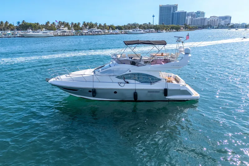 Slide: The Image of 2013 Azimut 45 Flybridge yacht cruising on clear blue waters near a marina. - 3