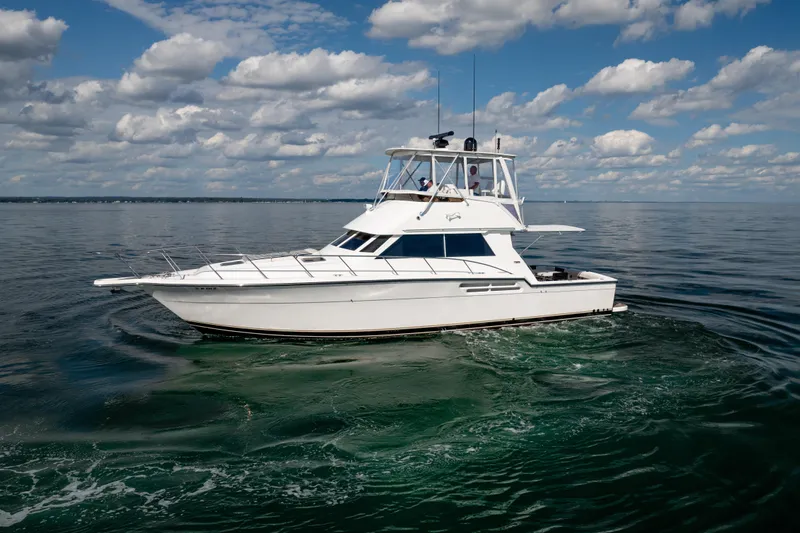 Slide: The Image of 2000 Tiara Yachts 4300 Convertible cruising on calm waters under a cloudy sky. - 11