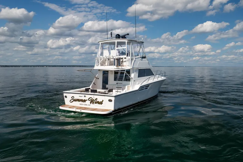 Slide: The Image of 2000 Tiara Yachts 4300 Convertible cruising on calm waters under a partly cloudy sky. - 23